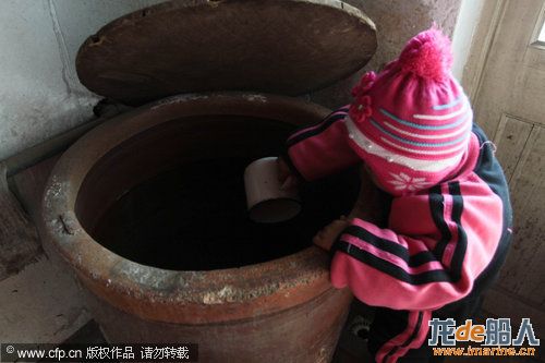 Dong Xinyi, of Huangjia town of East Chinas Shandong province, dips out water from a vat at home,  ...