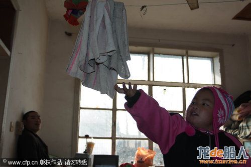  Three-year-old Dong Xinyi grabs a towel for her father, who is paraplegic, Dec 19, 2010. [Photo/CFP ...